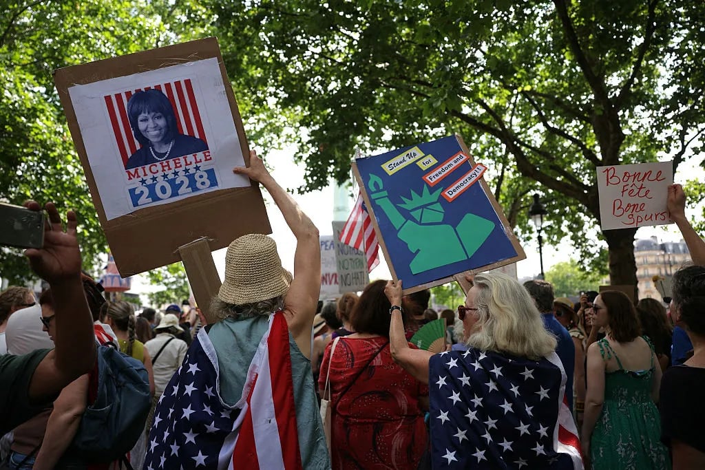 Demonstrators hold placards during a "No Kings" protest that underscore America's deep divisions over Trump's second term, at the Place de la Bastille in Paris on June 14, 2025. President Donald Trump presides over a huge military parade in Washington on his 79th birthday on June 14, 2025, as nationwide "No Kings" protests underscore America's deep divisions over his second term.