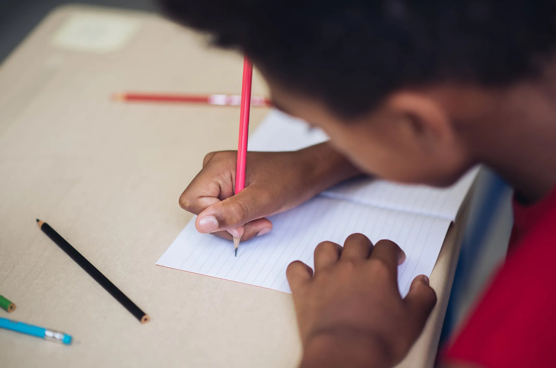 Close-up of young boy writing in classroom