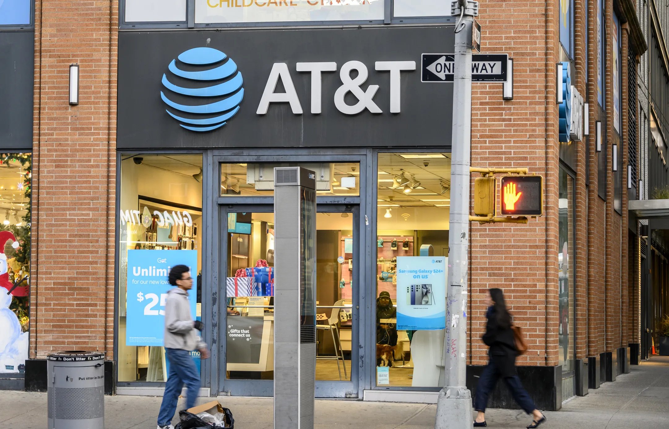 New York, New York, USA - November 18, 2024: People can be seen walking on Sixth Avenue in front of the AT&amp;T store.