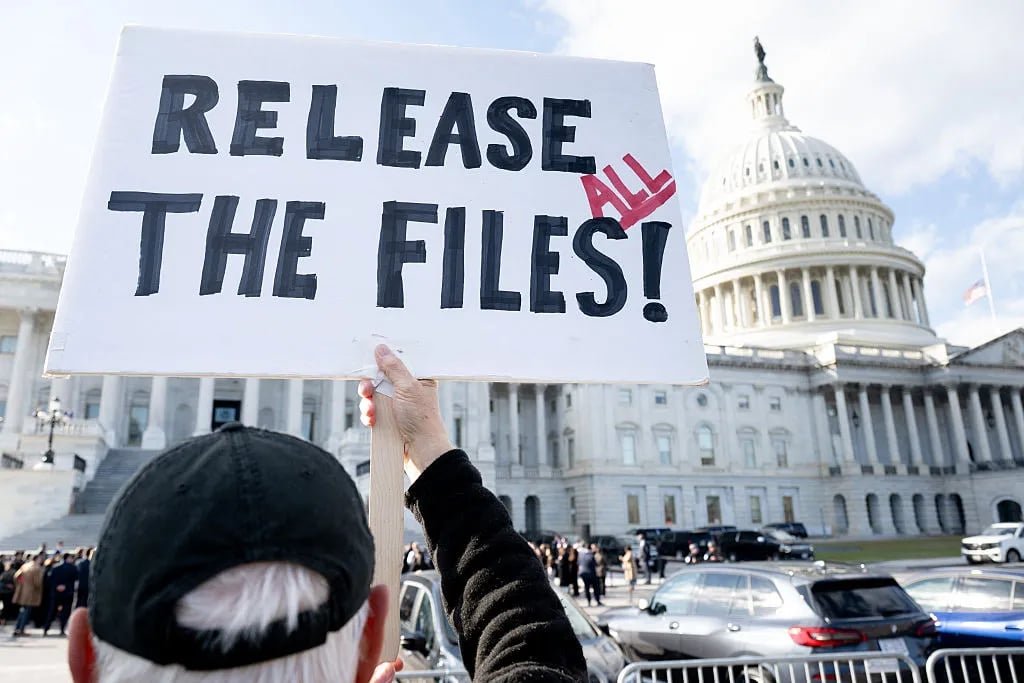 A protester holds a sign related to the release of the Jeffrey Epstein case files