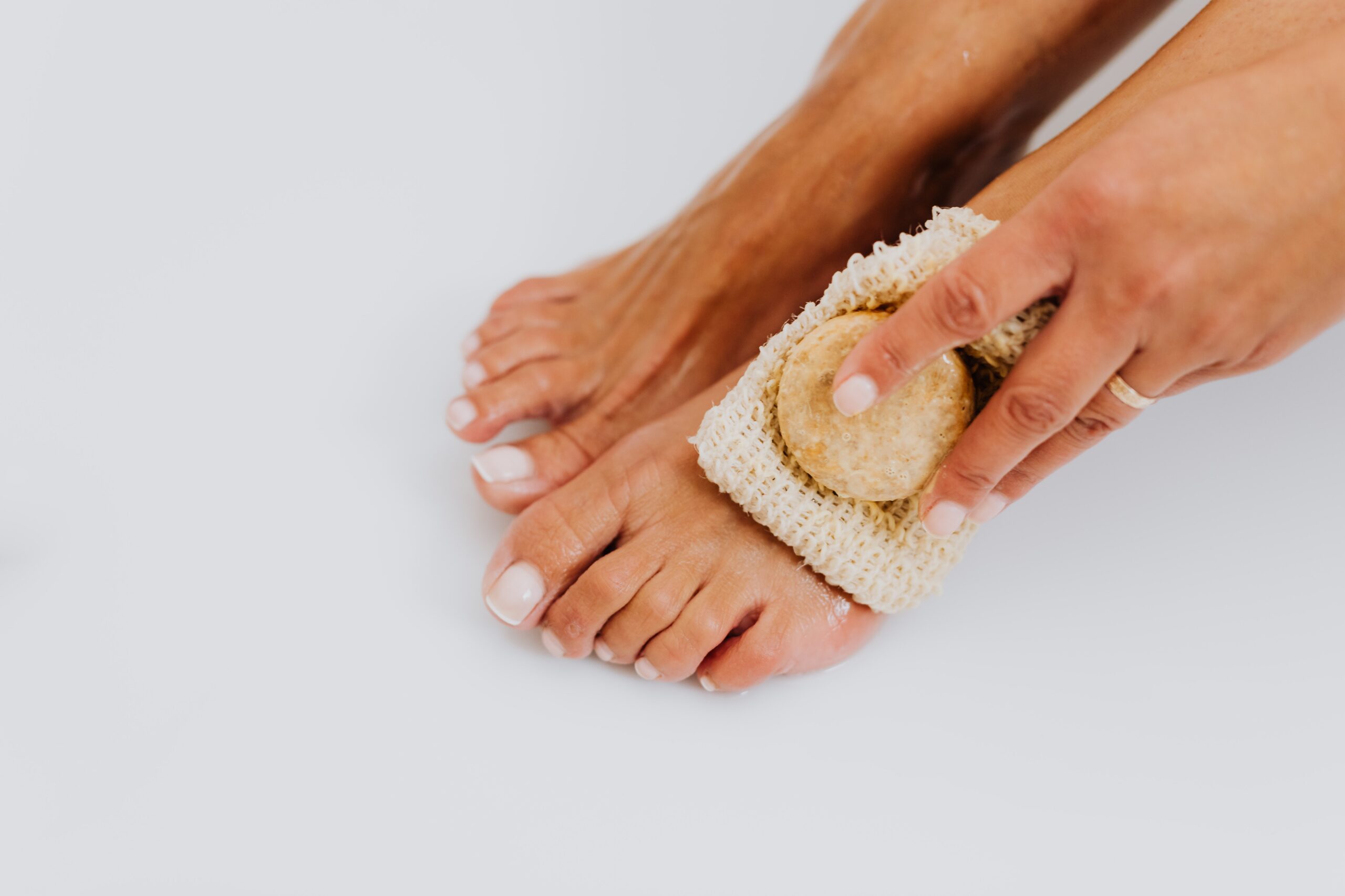 woman feet loofa grey background