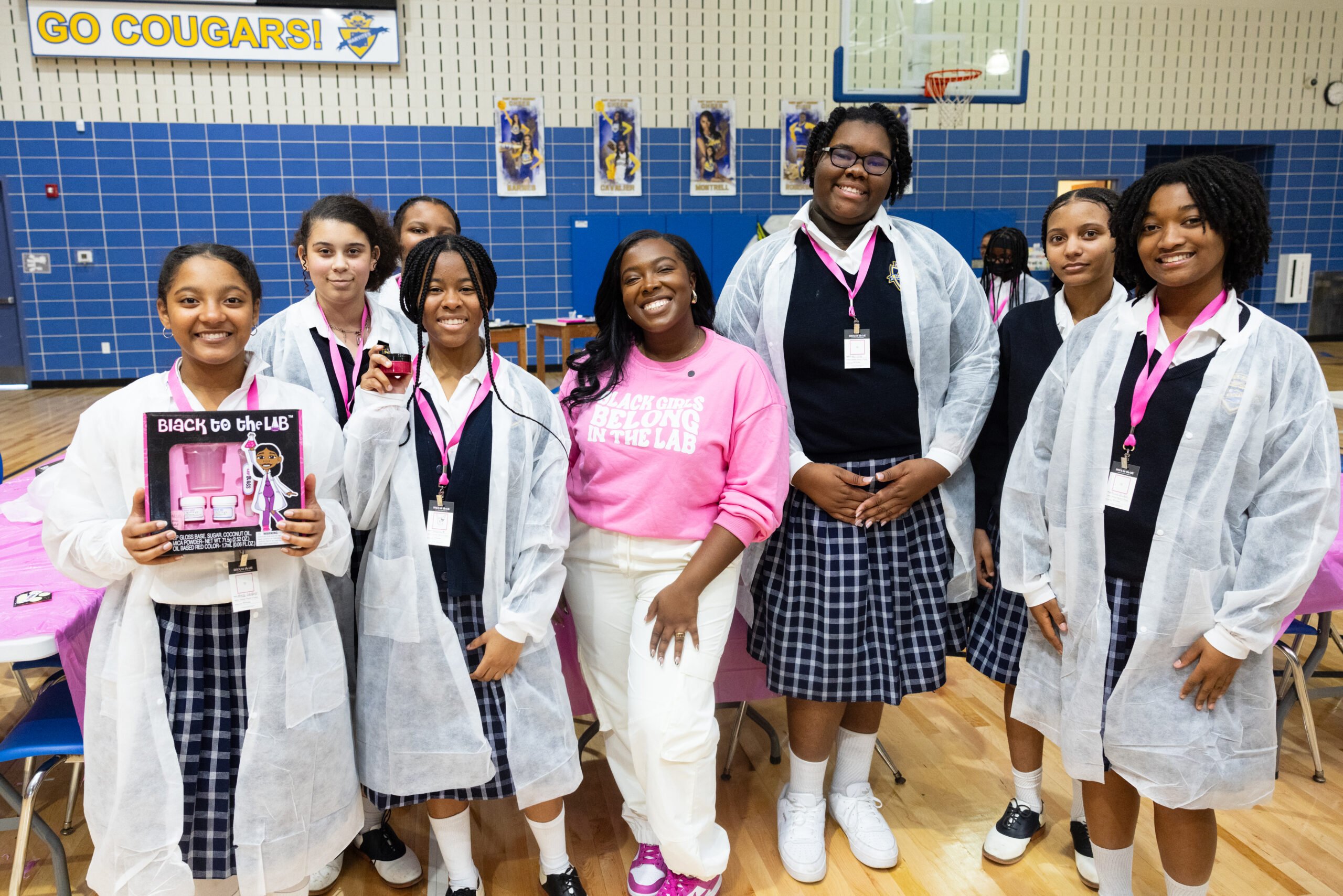 A female entrepreneur posing with students in lab coats