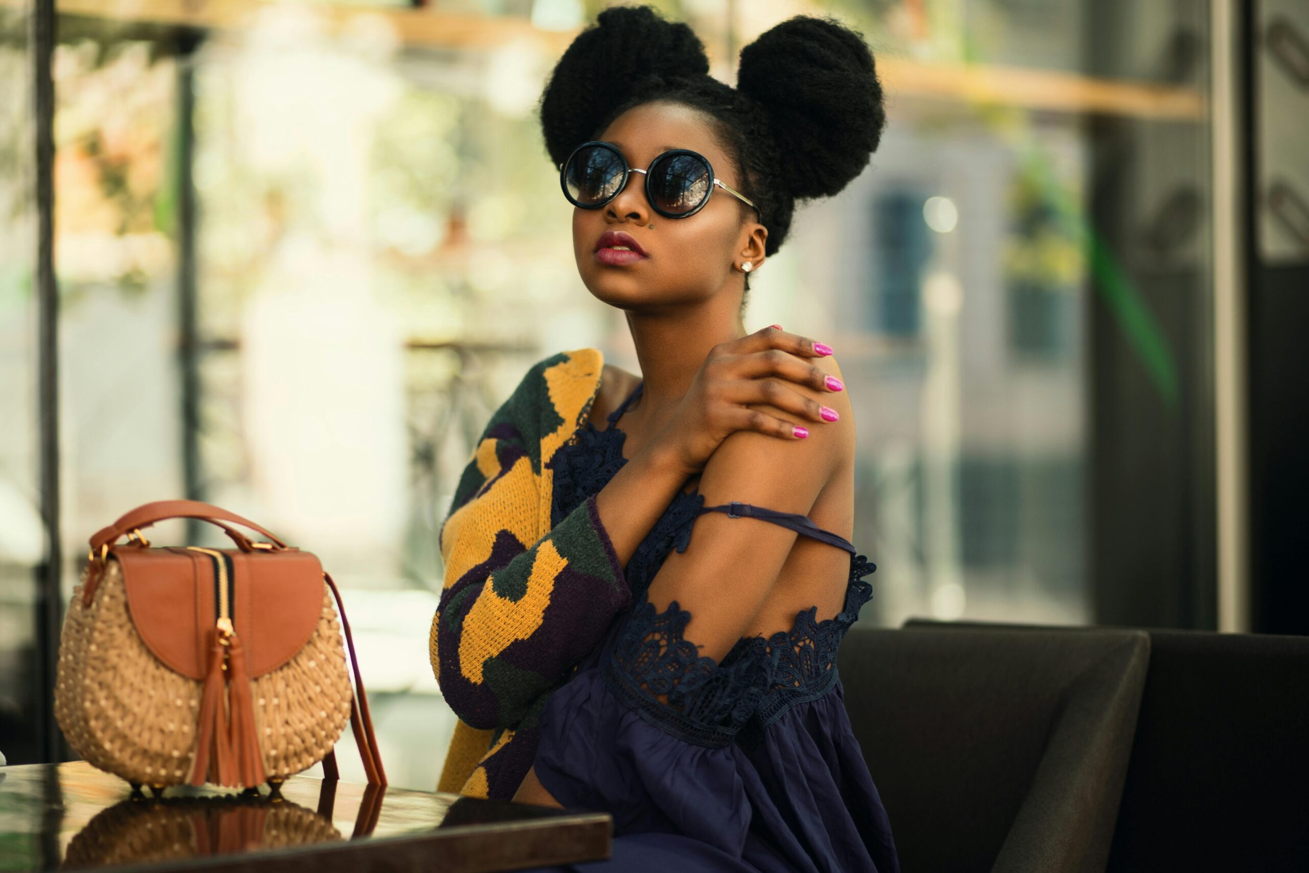 A picture of a Black woman wearing black round-frame sunglasses. best luxury sunglasses