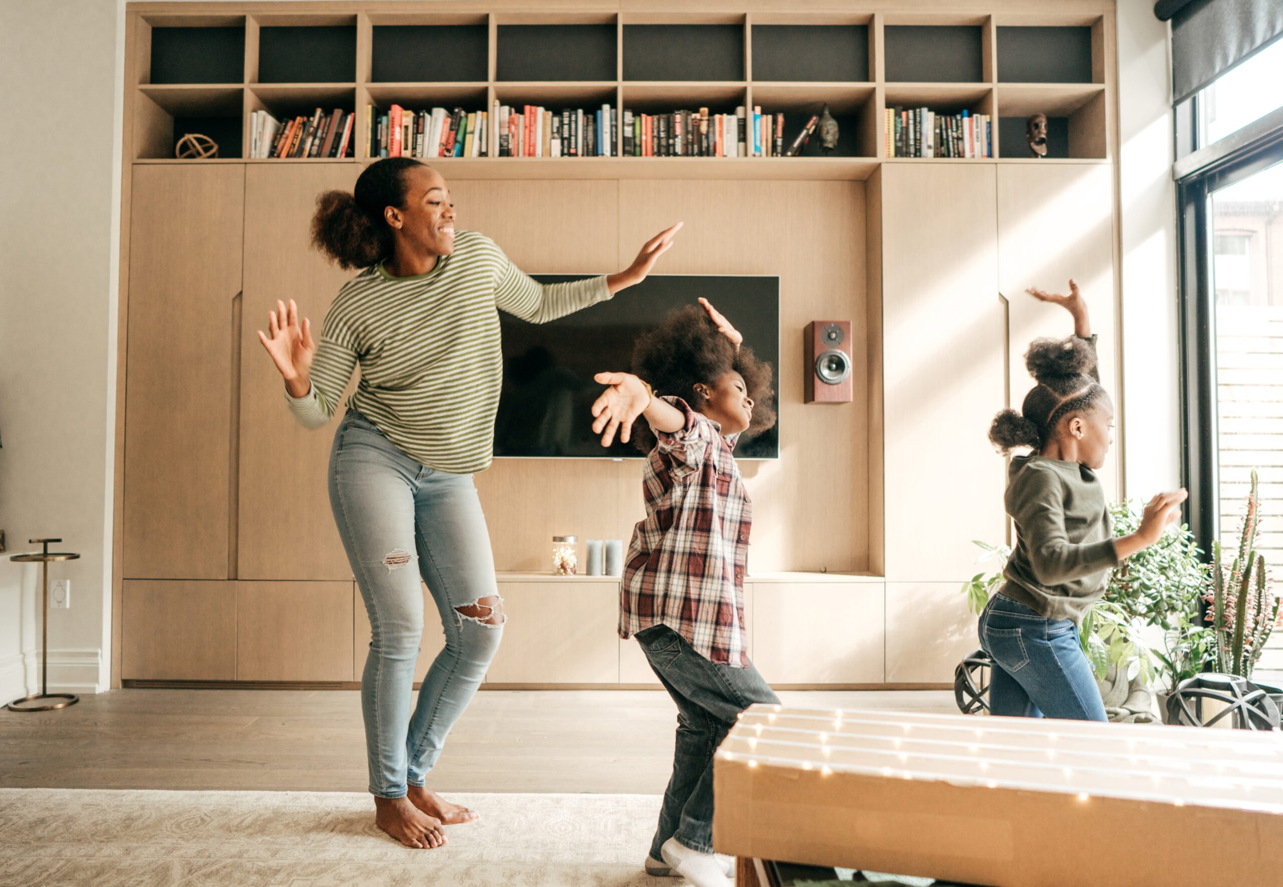 Mother and children dancing in a care free way in the living room.