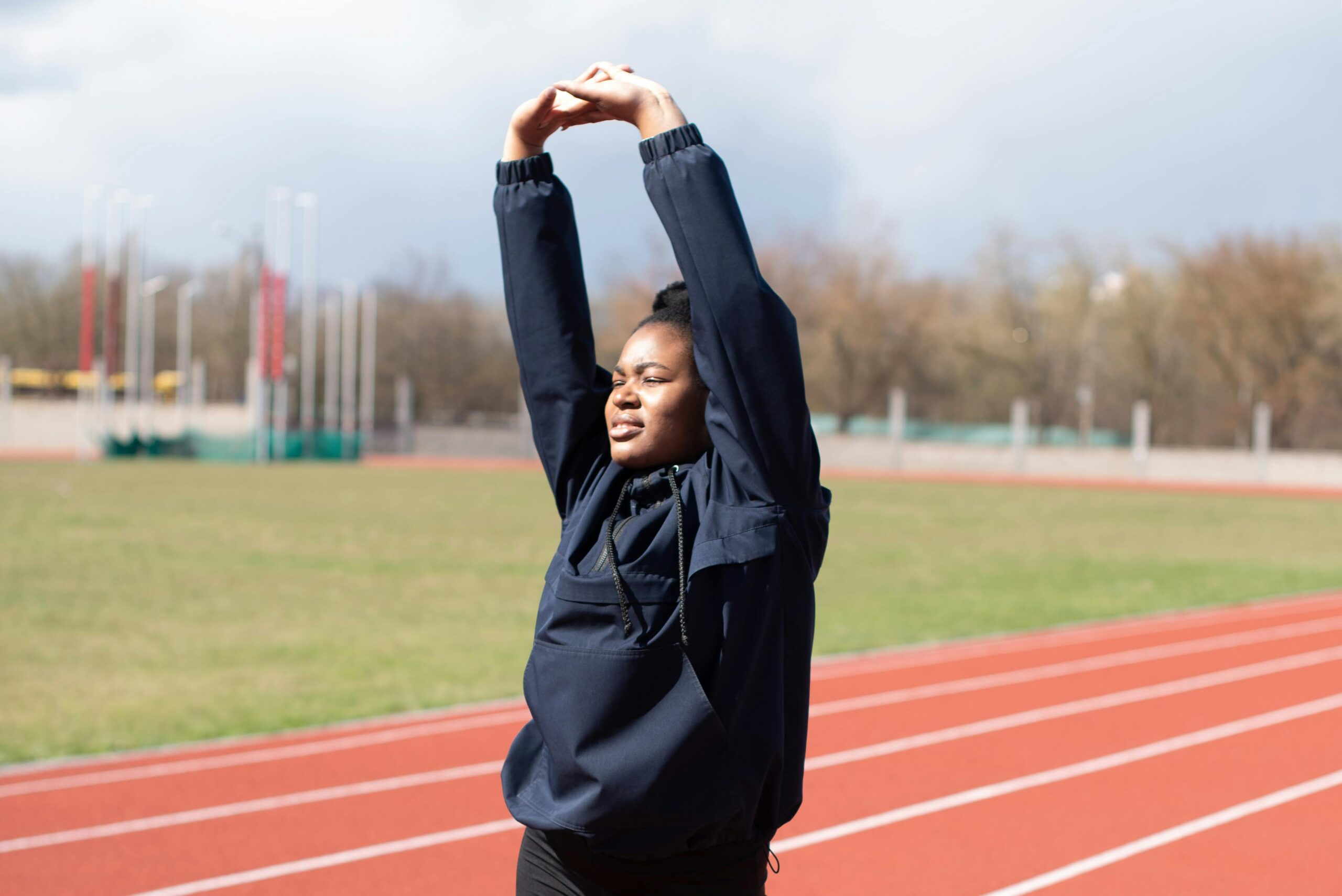 Black woman on a track stretching her arms. arm-stretches