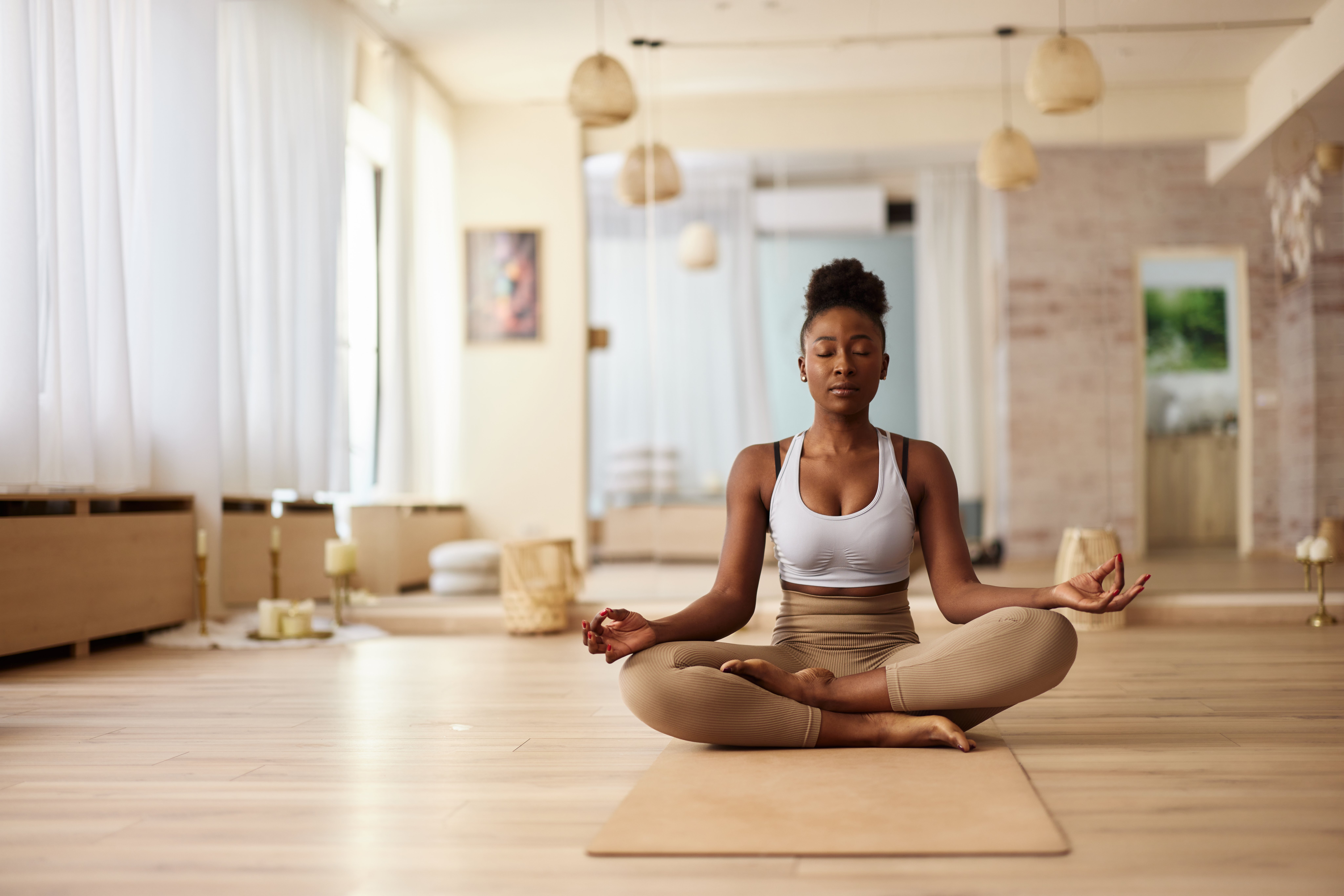 Young black woman doing Yoga meditation exercises in Lotus position at health club