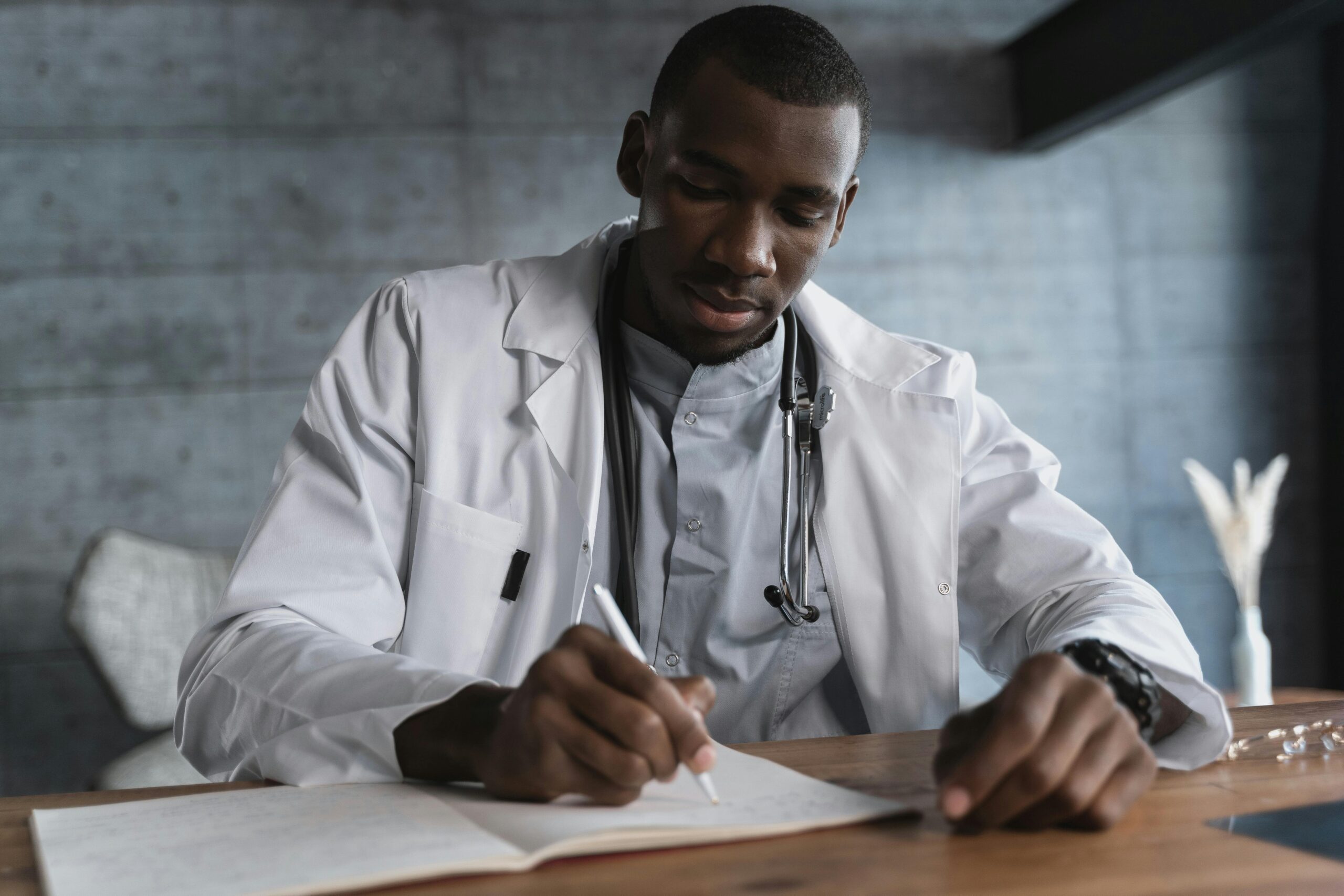 A Black Doctor in White Coat Writing about epilepsy at the Table