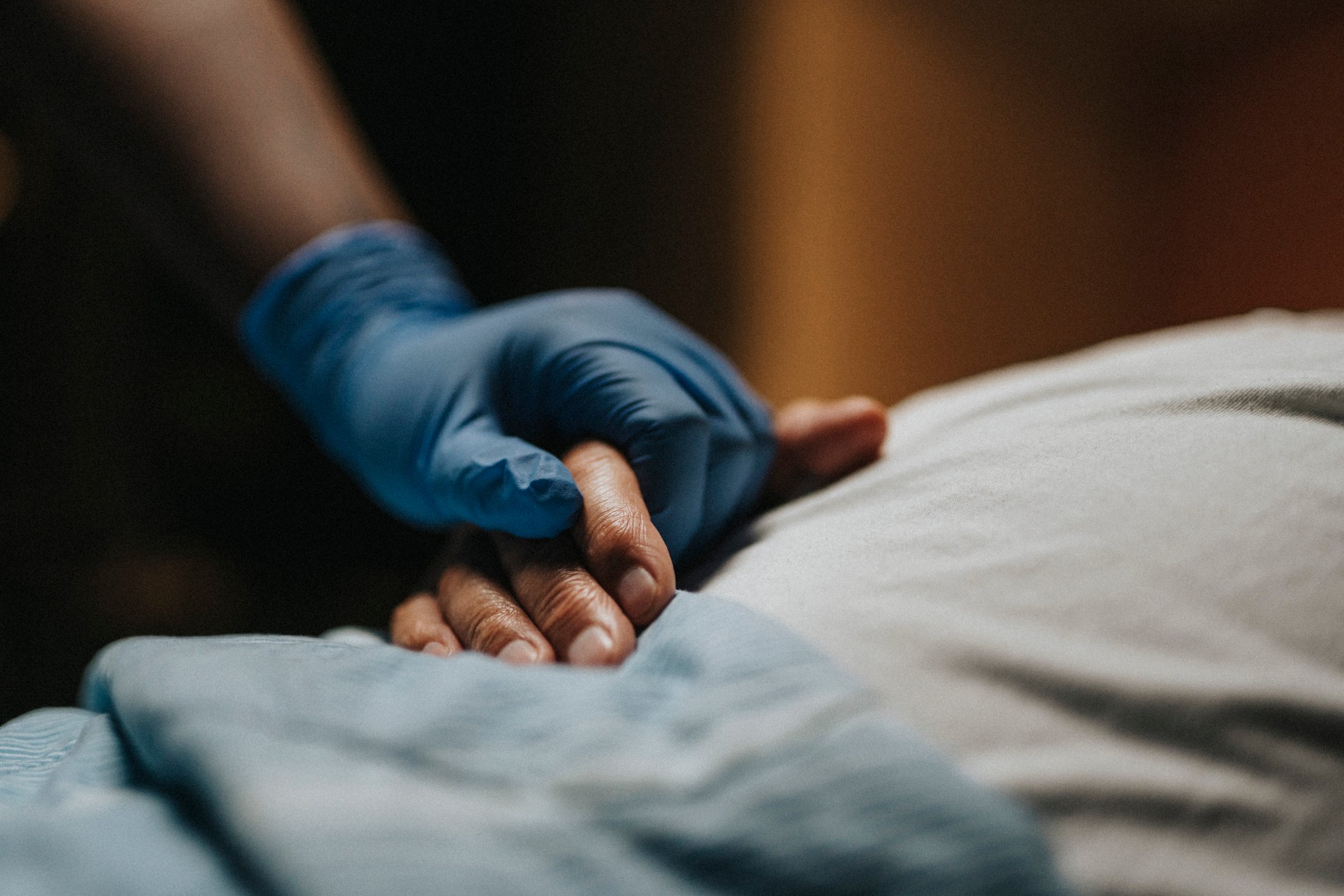 Medical staff wearing surgical glove holding hand of patient at clinic