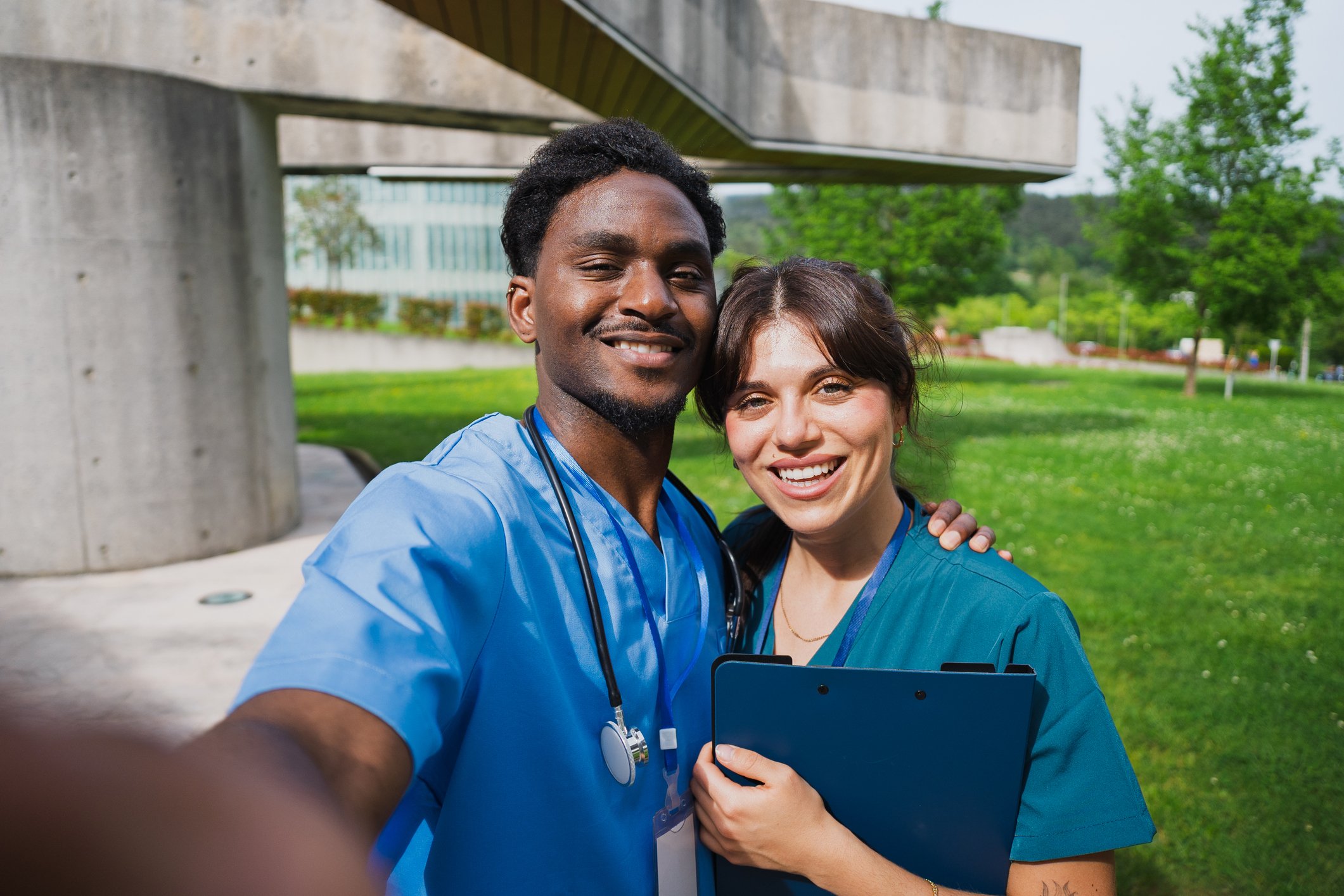 Young adult multiracial healthcare students smiling at camera, embracing friendship and unity in front of a modern building