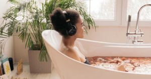 Black women with headphones on in the bathtub