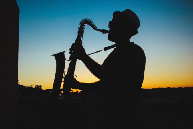 The silhouette of a man playing a horned instrument