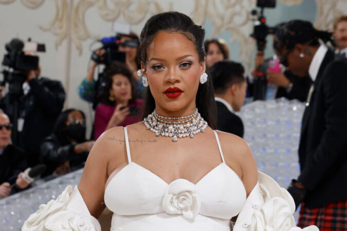 Rihanna at 2023 Met Gala with red lipstick, a white dress and a diamond necklace