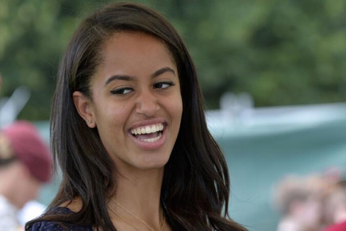 Malia Obama, daughter of US President, (R) smiles as she serves food during a lunch at the United States and Nato military base in Aviano on June 19, 2015 .   AFP PHOTO / ANDREAS SOLAROANDREAS SOLARO/AFP/Getty Images