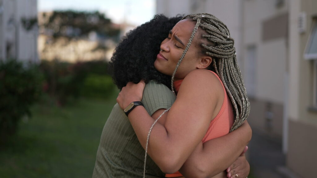 Two black women hugging after breaking up gracefully