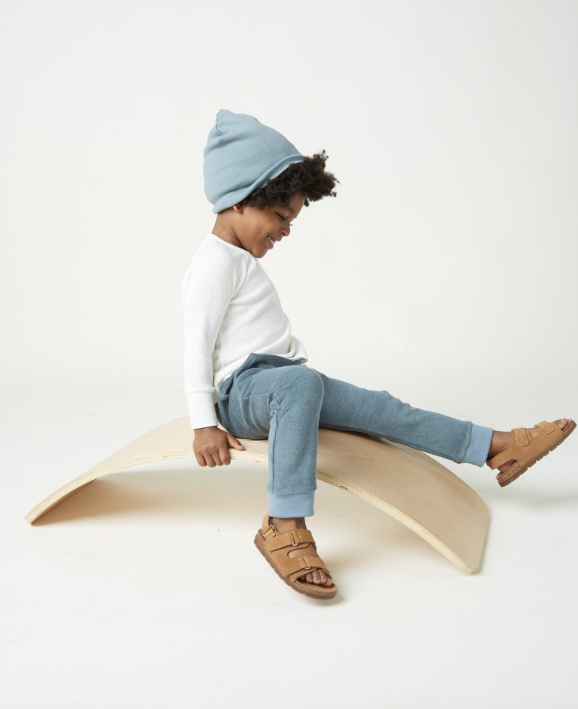 A kid with a beanie seated on an arch