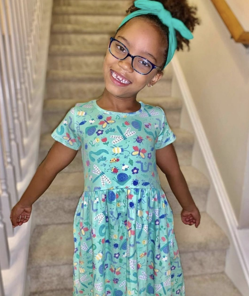 A little girl wearing a dress with bug designs