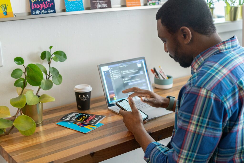 Millenial Pause x Gen Z Shake pictured: man scrolling on his phone in front of a laptop