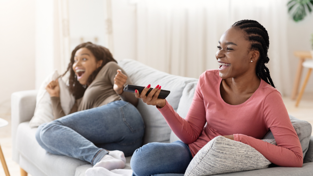 Joyful african girls watching TV at home 