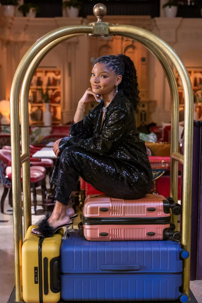 Halle Bailey sitting on top of suitcases