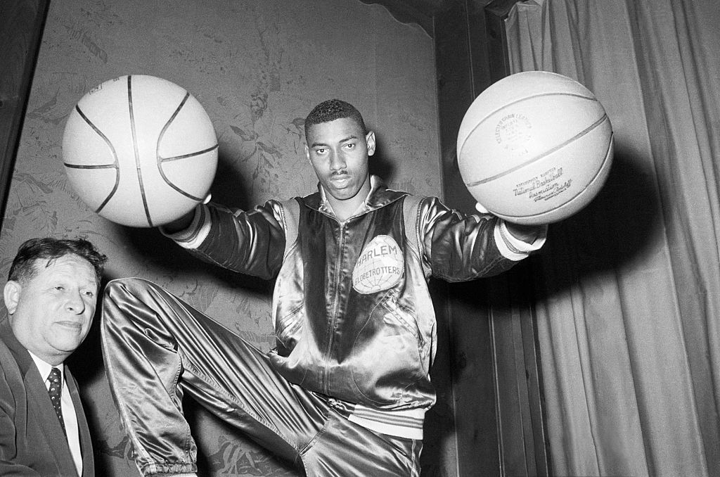 Wilt "The Stilt" Chamberlain, twice All-American at the University of Kansas, bedazzles Harlem Globetrotters' boss Abe Saperstein (R) with his basketball palming technique, after it was announced that Chamberlain had signed to play for the famous all-Negro team for a record high of $65,000 for one season.