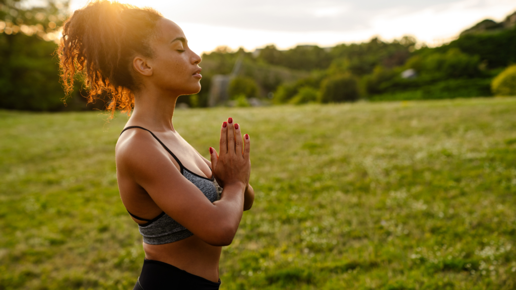 Young Black Woman Meditating during Yoga Practice outdoors on a sunny day