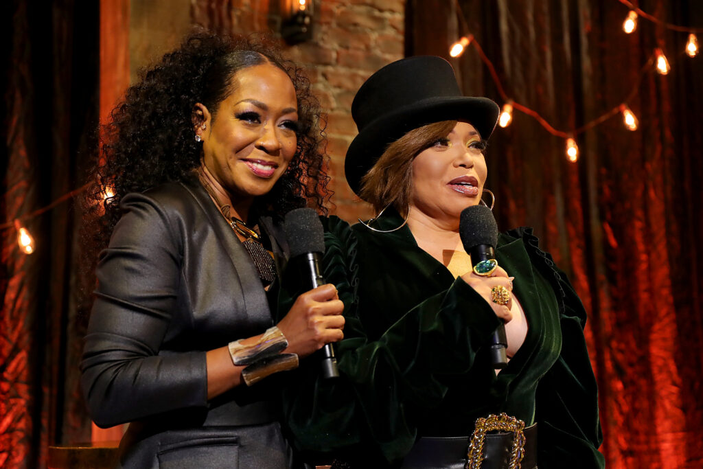 On November 29th, Tisha Campbell  and Tichina Arnold speak during the 2020 Soul Train Awards presented by BET. Both are dressed in all black jackets while Tisha wears a top hat. 