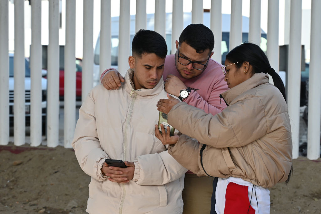 Asylum seekers check their phones as they wait for a CBP One appointment at the El Chaparral border port in Tijuana, Mexico, on January 20, 2025. US President Donald Trump, during his inauguration, says that he will issue a raft of executive orders aimed at reshaping citizenship and immigration, starting with the asylum process, among others. The Trump administration shuts down the CBP One app for migrants. The Biden-era process allows nearly 1 million migrants to enter the US at legal border crossings since the app initiates. 