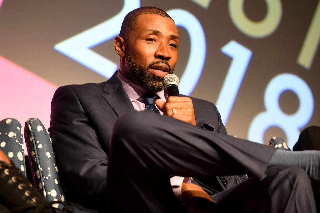 Actor Cress Williams, wearing a dark grey suit with a pink dress shirt, speaks during a screening and Q&A for 'Black Lightning' on Day 3 of the SCAD aTVfest 2018 on February 3, 2018 in Atlanta, Georgia.  