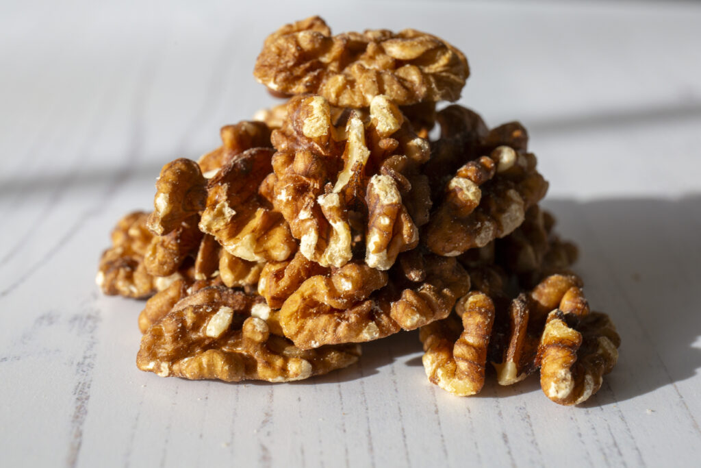 A small stack of walnuts on a white painted wooden surface.
