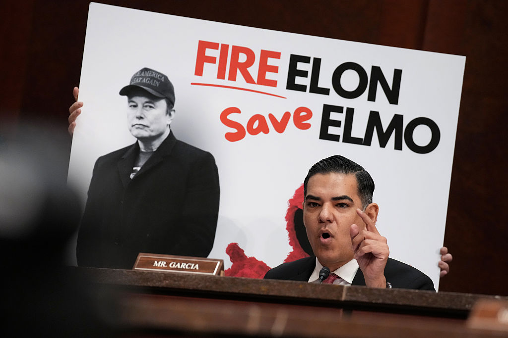 WASHINGTON, DC - MARCH 26: U.S. Rep. Robert Garcia (D-CA) speaks in front of poster of Tesla and SpaceX CEO Elon Musk during a House Oversight and Government Reform Committee hearing at the U.S. Capitol on March 26, 2025 in Washington, DC. The heads of NPR and PBS appeared before the House Subcommittee on Delivering on Government Efficiency to address allegations of bias in their programming against conservatives