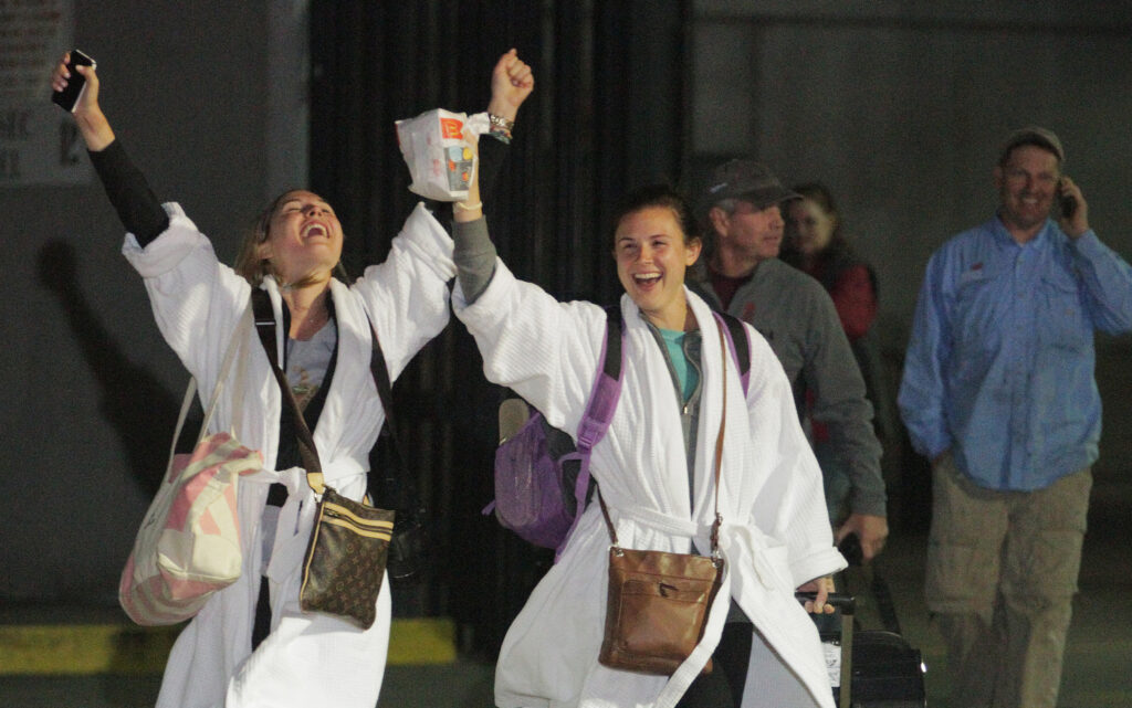 Kendall Jenkins (L) and friend cheer after stepping off the crippled Carnival ship Triumph at the Alabama Cruise terminal in Mobile, Alabama, on February 14, 2013.